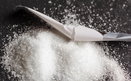 Белый порошок с ножом на тёмной поверхности